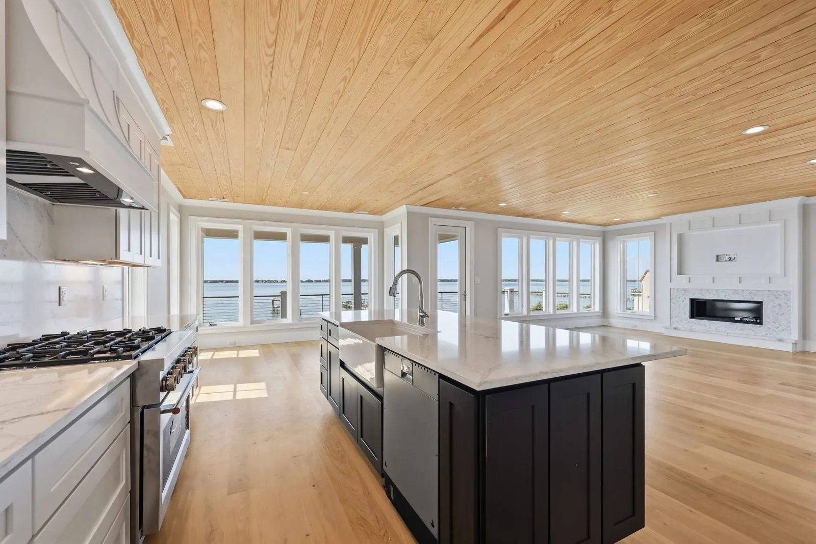 Kitchen with professional-style gas range, custom hood, dark island with farmhouse sink, and sound views