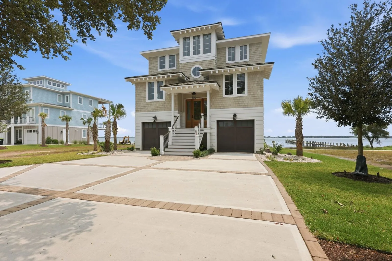 Street view of the house with banded concrete drive and palms